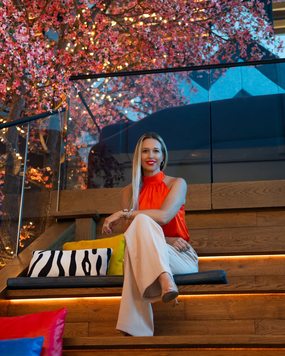 Dani Rebolo seated on wooden steps under a flowering tree
